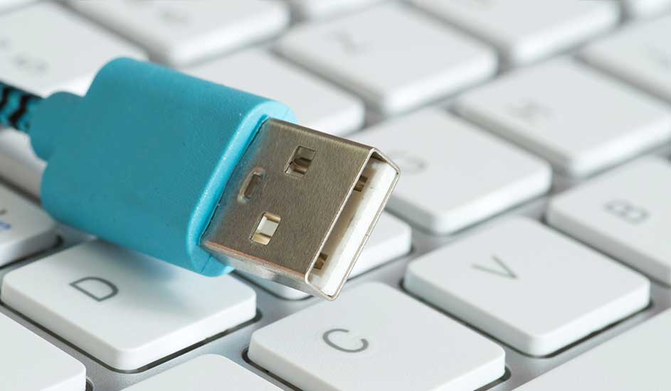 Un câble USB bleu clair repose sur un clavier blanc. Le connecteur USB est argenté avec des détails intérieurs blancs.