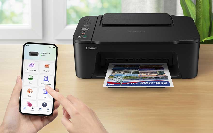 Een Canon-printer drukt een kleurrijke pagina af terwijl iemand via een smartphone de printer bedient. De printer staat op een houten tafel.