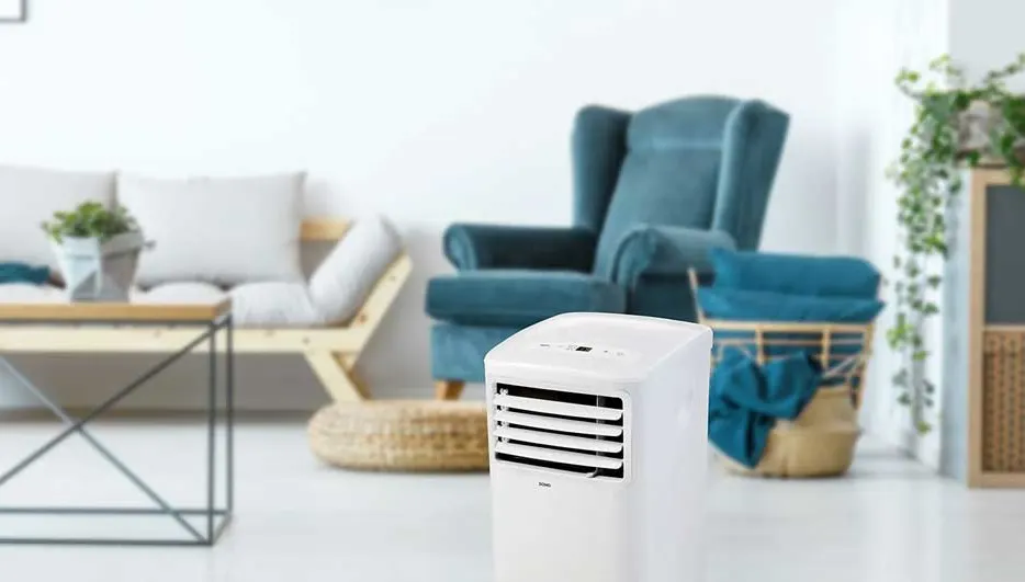 Climatiseur mobile Domo dans un salon moderne et lumineux, avec canapé, fauteuil et plantes ; marque Domo clairement visible.