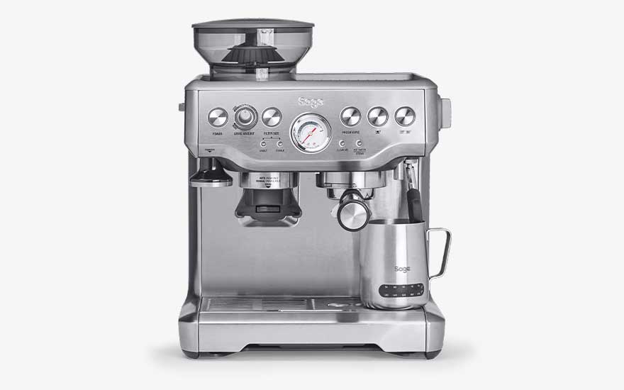 A silver Sage espresso machine includes a built-in grinder, pressure gauge, steam wand and metal milk jug on the drip tray.