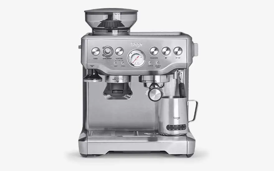 A silver Sage espresso machine includes a built-in grinder, pressure gauge, steam wand and metal milk jug on the drip tray.
