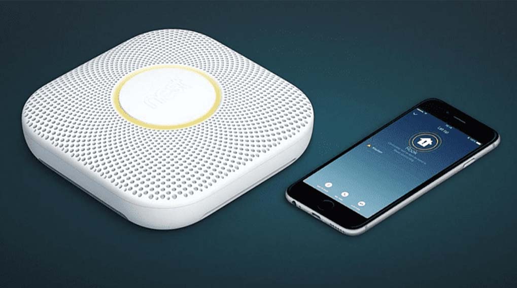 Un détecteur de fumée blanc avec un centre jaune et un téléphone intelligent noir sur fond bleu.