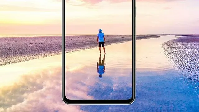 Een smartphone toont een strandscène bij zonsondergang, met water, zand en een reflectie.