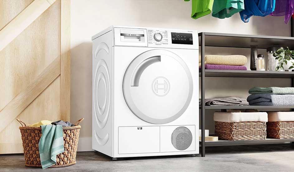 Un sèche-linge Bosch blanc dans une buanderie avec des étagères remplies de serviettes, un panier à linge et des vêtements colorés qui sèchent.