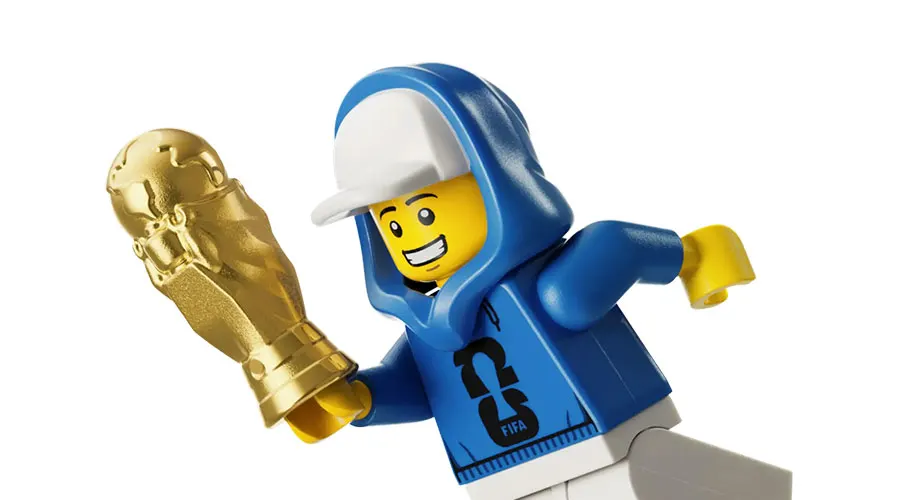 Minifigurine LEGO en sweat à capuche bleu tenant un trophée doré de la Coupe du monde.