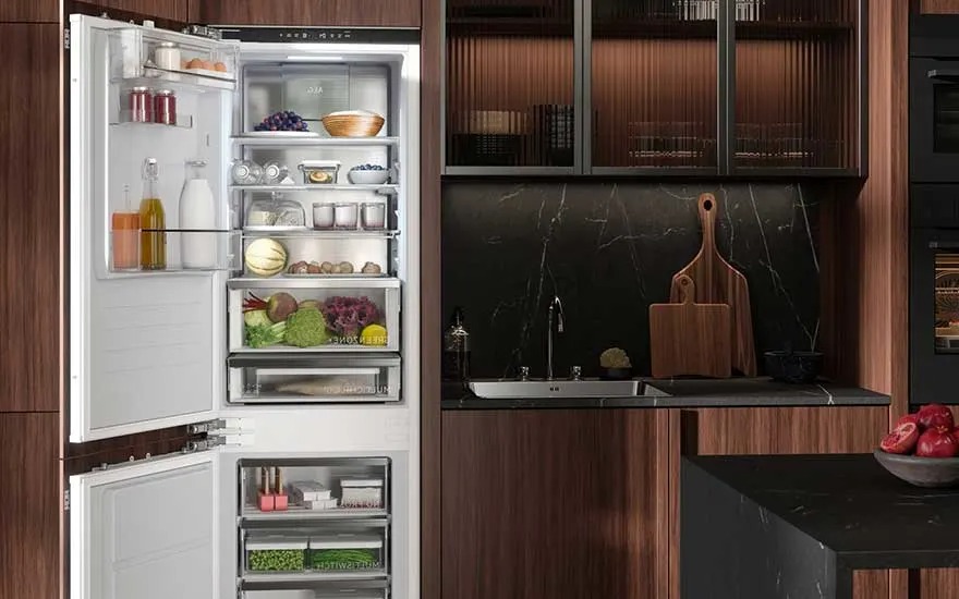 Een open AEG inbouwkoelkast vol groenten, fruit, flessen en bakjes staat in een luxe keuken met donkere houten kasten.