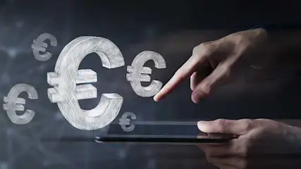 Hands hover over a tablet as floating chalk-style euro symbols emerge from the screen, suggesting digital finance or mobile payments. No brand shown.
