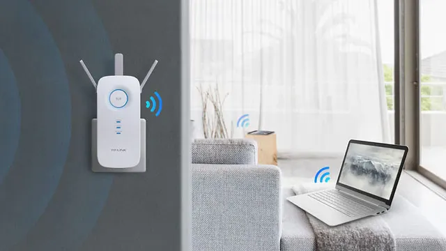 Un amplificateur Wi-Fi blanc est branché au mur. Un ordinateur portable gris est sur un canapé près d'une fenêtre.