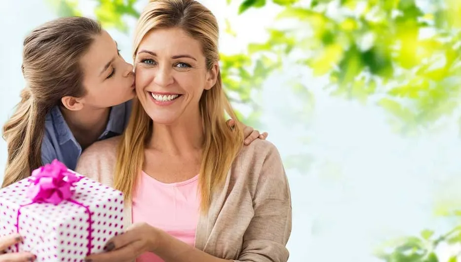 Une femme reçoit un cadeau avec un ruban rose, sur un fond vert clair et blanc flou.