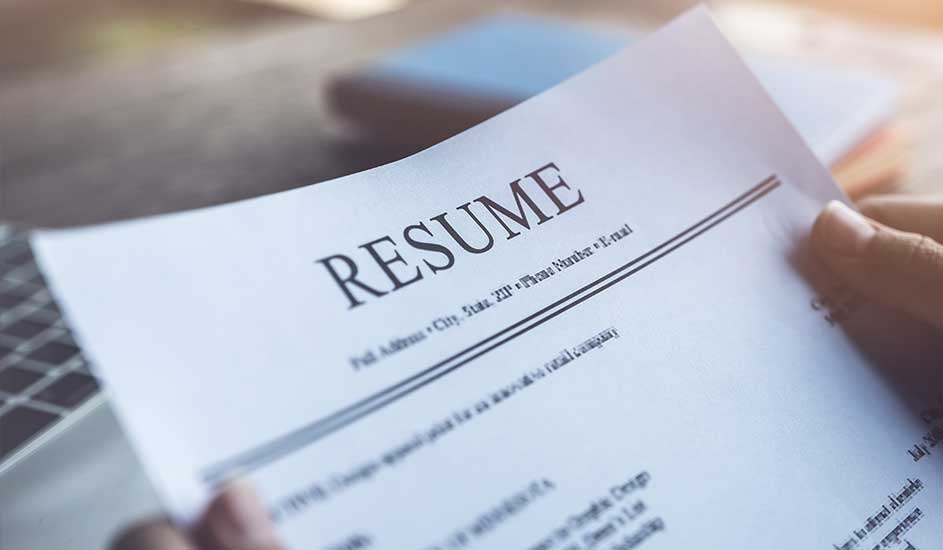 Een wit blad papier met de tekst "RESUME" in grote, zwarte letters bovenaan, ligt op een bureau.