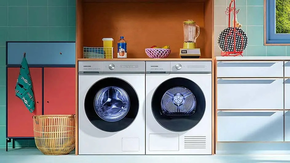 Buanderie lumineuse avec deux machines à laver blanches, des meubles colorés et des accessoires sur une étagère en bois.