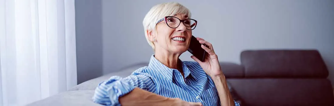 A woman sits on a sofa, having a relaxed phone call.