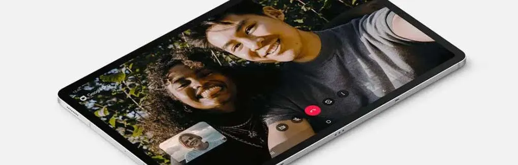 Écran de tablette affichant un appel vidéo avec deux participants, sur fond de feuillage extérieur.