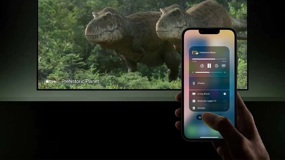 Een iPhone toont afspeelbediening voor "Prehistoric Planet" op een tv-scherm met dinosauriërs en groen op de achtergrond.