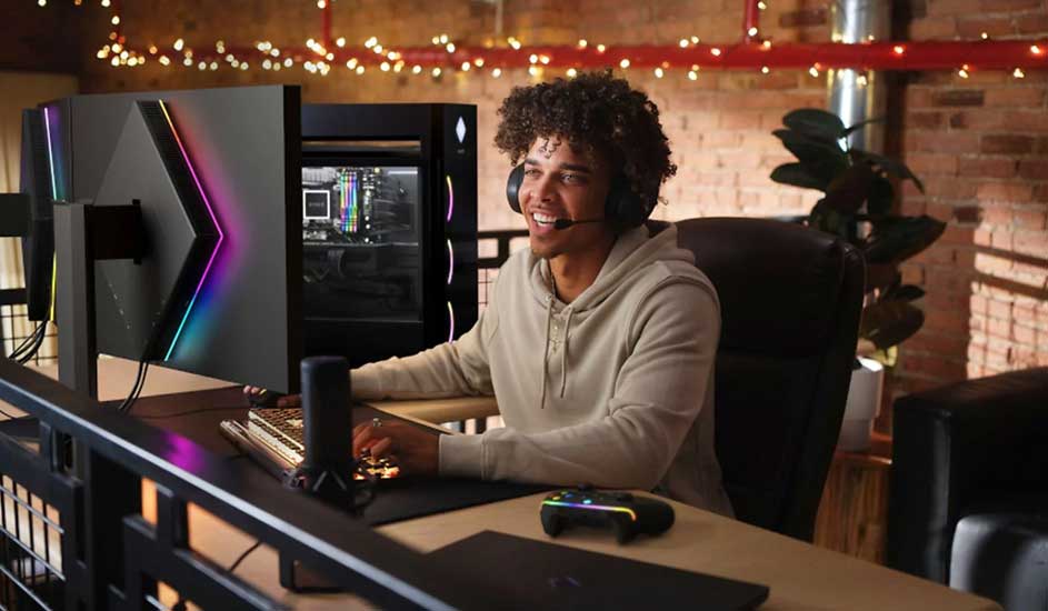 Een gamingcomputer met een monitor met regenboogkleuren staat op een bureau, met een toetsenbord en een controller.