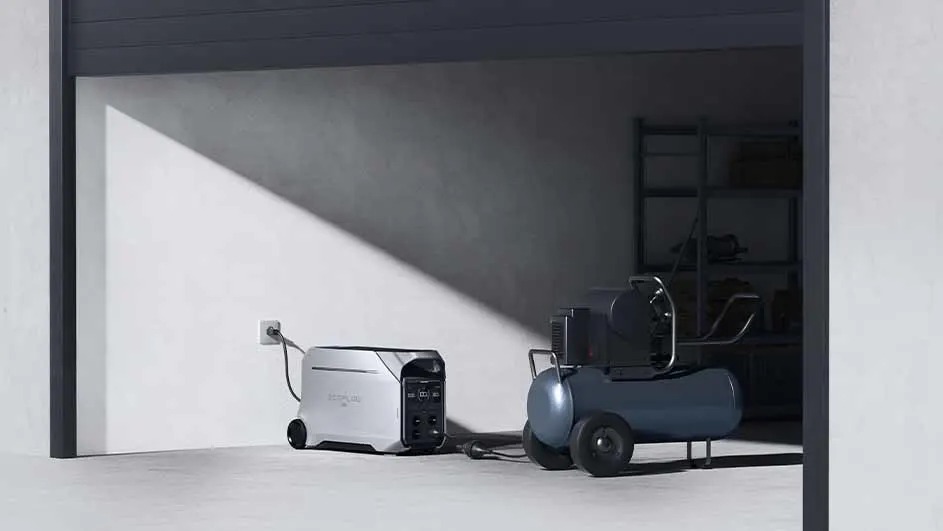 Dans un garage, un compresseur bleu et une alimentation électrique portable argentée sont visibles.