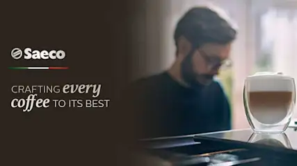 Tasse de café à trois couches sur une table noire. Logo Saeco en haut à gauche sur fond sombre.