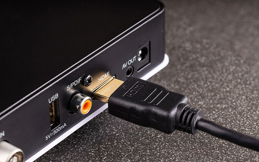 Boîtier noir avec ports USB, S/PDIF, HDMI et AV OUT. Un câble HDMI noir est branché dans le port HDMI.