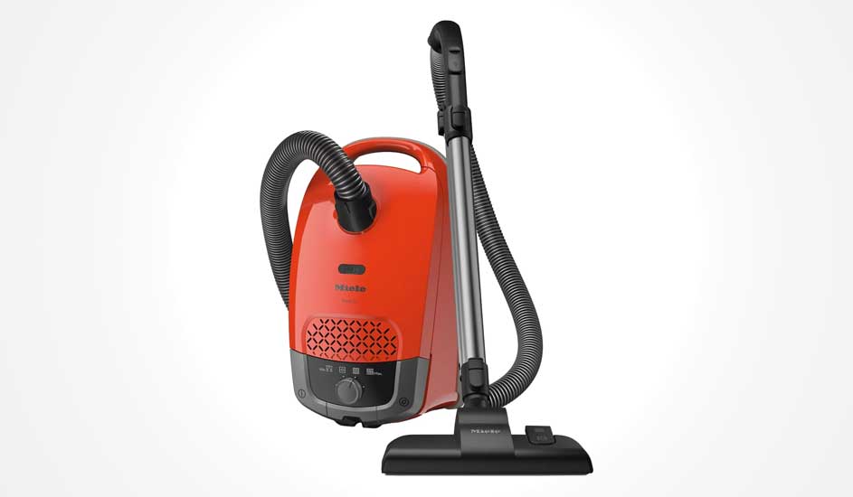 Een rode Miele sledestofzuiger met zwart handvat, flexibele slang en zilveren telescoopbuis staat rechtop op een witte achtergrond.