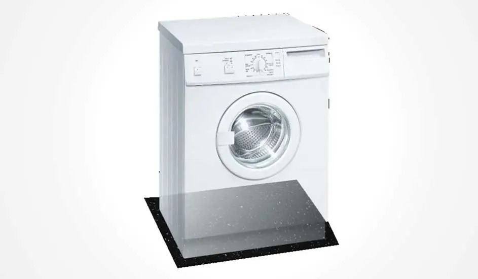 Een witte wasmachine staat op een zwart dempend plateau, het bedieningspaneel en de deur zijn duidelijk zichtbaar, merk is niet zichtbaar.