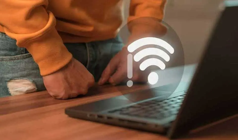 Iemand in een oranje trui staat bij een laptop, met een wifi-symbool dat draadloze verbinding voorstelt.