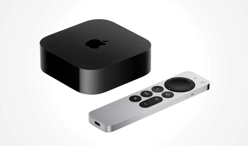 Een zwarte Apple TV-box met afgeronde hoeken en een zilveren afstandsbediening ervoor.