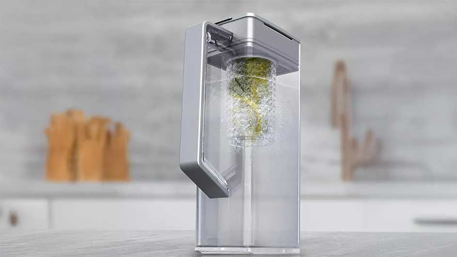 Carafe d'eau transparente avec filtre vert, sur une surface de cuisine grise. Arrière-plan flou.