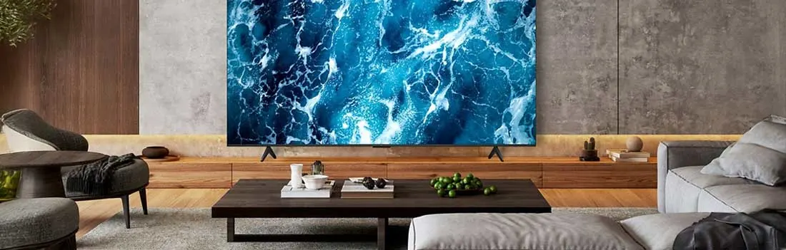 Een grote tv toont een abstracte blauwe zeeprint in een stijlvolle woonkamer met lage tafel, bank en houten accenten.