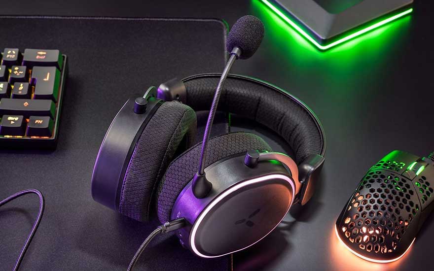 Een close-up toont een zwarte hoofdtelefoon met microfoon, een gamingmuis, en een toetsenbord op een donkere achtergrond met groene accentverlichting.