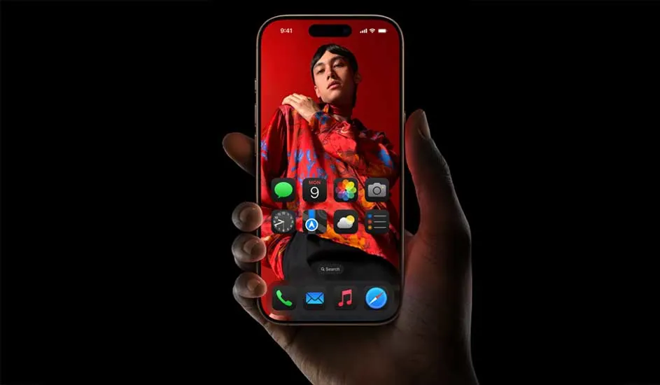Een hand houdt een Apple iPhone vast met een kleurrijke achtergrond en duidelijke app-iconen op het scherm tegen een zwarte achtergrond.