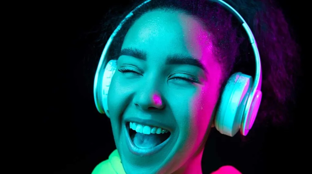 Gros plan d'un casque blanc sur fond noir, éclairé en bleu et rose.