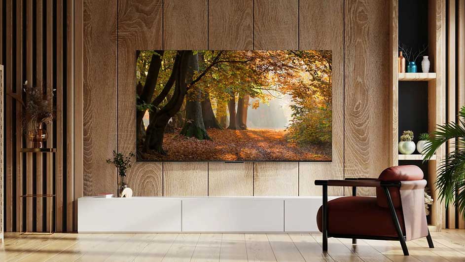 Intérieur avec TV affichant une forêt d'automne, meuble TV blanc et fauteuil marron. Murs en bois et étagères décoratives.