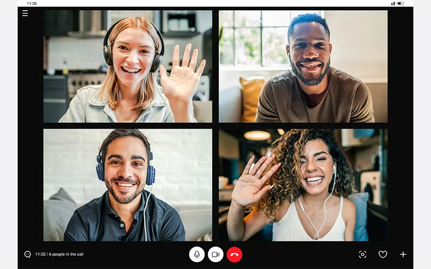Quatre écrans affichent des personnes souriantes, mains levées, lors d'un appel vidéo sur un appareil numérique.