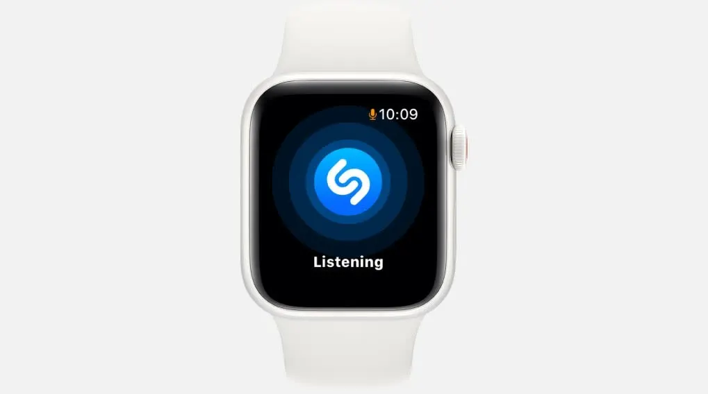 Een witte smartwatch toont een blauw Shazam-logo op een zwart scherm, met de tekst "Listening" eronder. De tijd is 10:09.