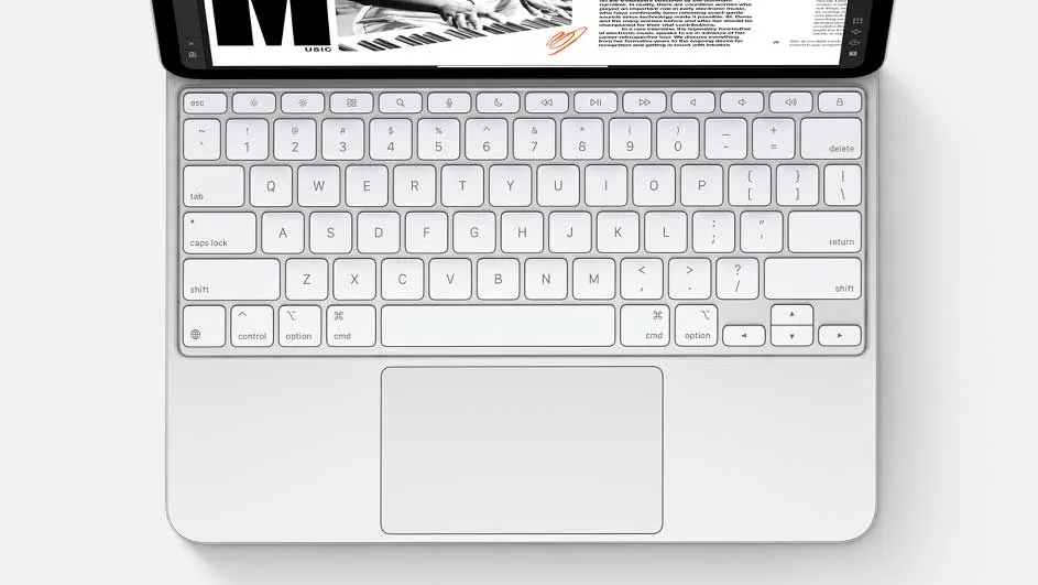 Vue de dessus d'un clavier blanc avec pavé tactile intégré, connecté à une tablette affichant du texte et une image en noir et blanc.