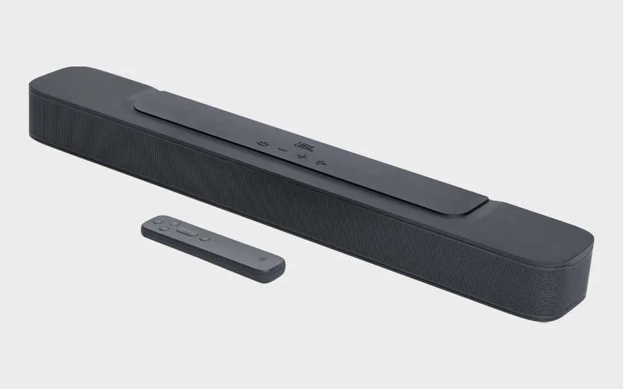 Une barre de son JBL noire avec télécommande est présentée en perspective sur fond clair, avec une allure moderne et discrète.