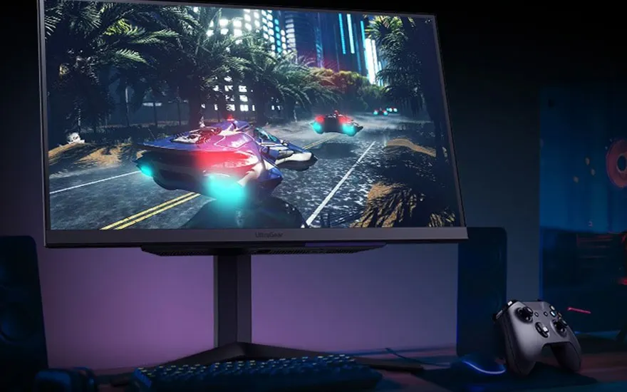 Écran avec jeu vidéo affichant des voitures sur une route urbaine bordée de palmiers et gratte-ciel, avec clavier et manette en avant-plan.