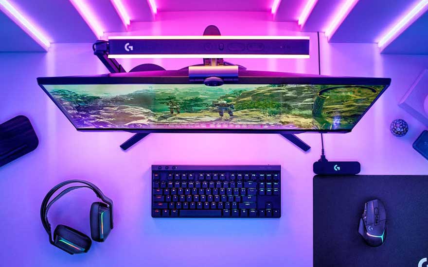 Een complete Logitech G gaming setup van bovenaf met headset, toetsenbord, muis en monitor, alles verlicht met paarse en blauwe RGB-verlichting.