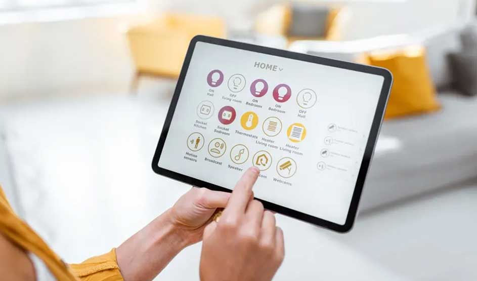 Une personne utilise une tablette pour contrôler une maison intelligente. L'écran affiche des icônes pour l'éclairage, le chauffage et la sécurité.