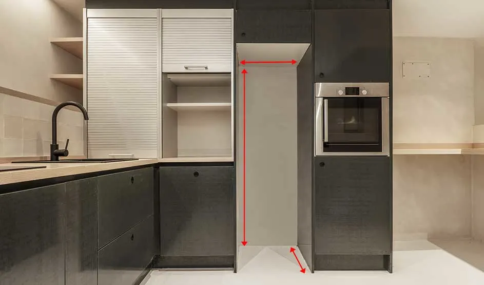 Une cuisine moderne montre une niche étroite entre des placards et un four, avec des flèches rouges pour les dimensions.