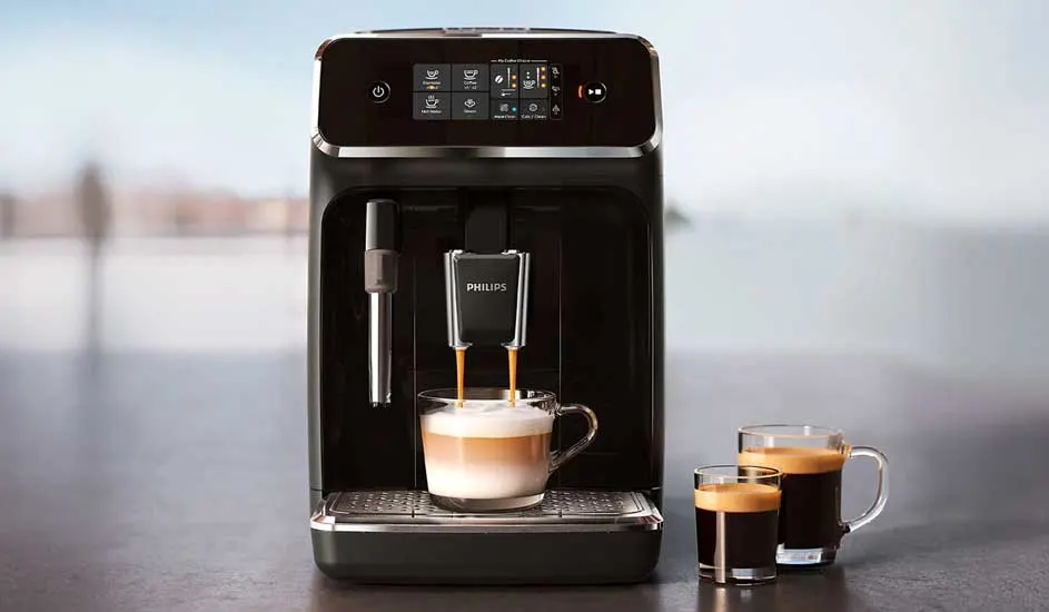 Gros plan d'une machine à café argentée avec écran LCD affichant "GRIND", "SHOT", une main ajustant le bouton "GRIND AMOUNT".