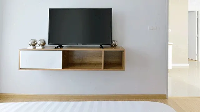 Een zwarte tv staat op een houten kast met een witte lade aan een witte muur in een kamer.