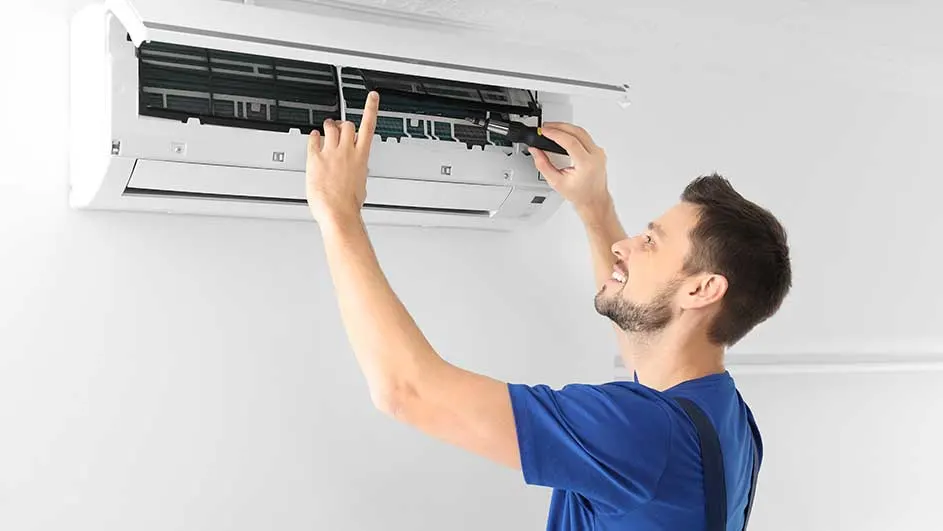 Een witte airconditioner hangt aan een witte muur, open voor onderhoud.