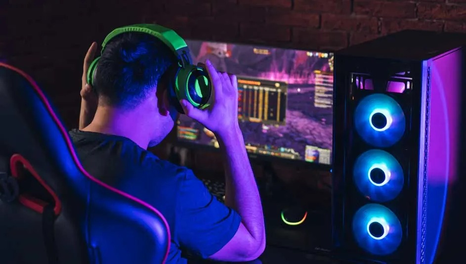 Un écran d'ordinateur affiche un jeu vidéo, avec une tour d'ordinateur à LED bleues et un casque vert.