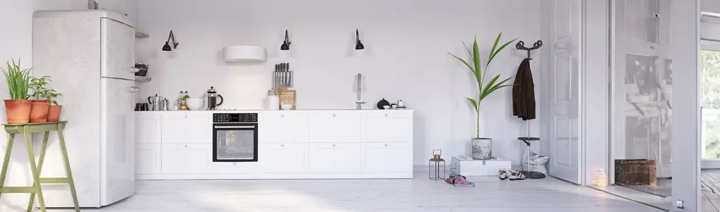 Cuisine lumineuse et épurée avec meubles blancs, plantes vertes et détails noirs. Réfrigérateur blanc à gauche, four noir intégré.