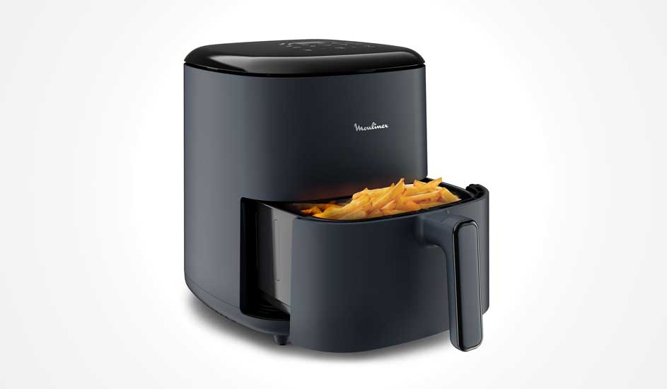 Une friteuse à air noire Moulinex avec tiroir ouvert rempli de frites est posée sur fond clair.