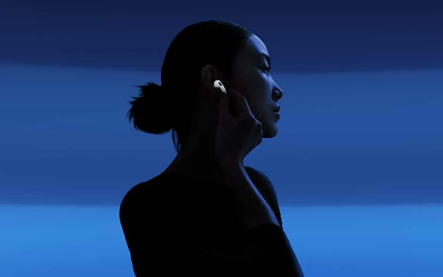 Sur des nuances de bleu profond, la silhouette d’une personne effleure un écouteur blanc lumineux, dans une ambiance d’écoute apaisée.