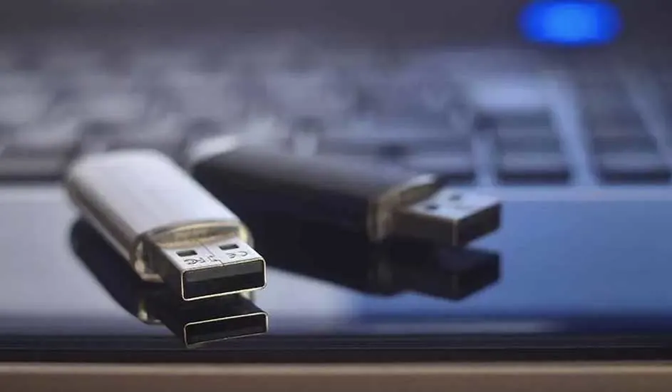 Deux clés USB, une argentée et une noire, reposent sur un clavier flou.
