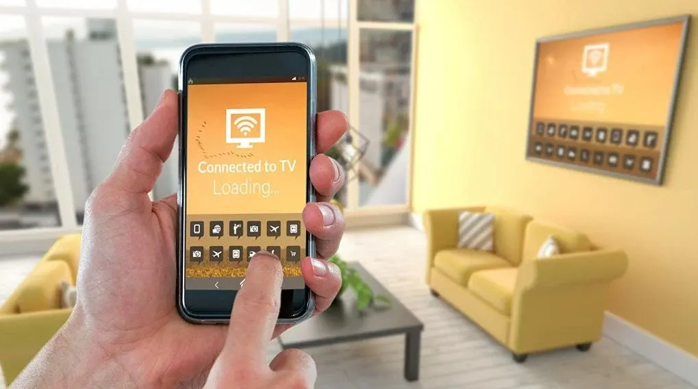Main tenant un smartphone affichant « Connecté à la TV ». Canapé et TV jaunes en arrière-plan.