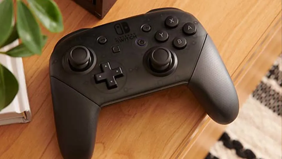 Zwarte Nintendo Switch Pro Controller op een houten tafel, met links een plant en boeken.